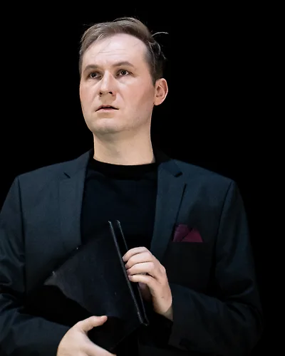Semjon Bulinsky als Don Ottavio, allein im schwarzen Sakko vor schwarzem Grund