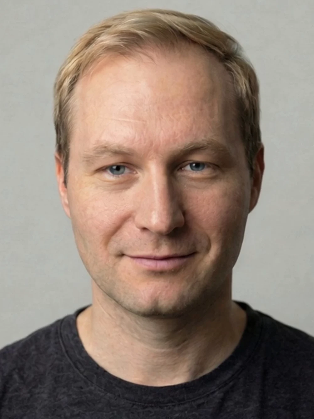 Porträt von Semjon Bulinsky vor grauem Studiohintergrund, im dunklen Shirt, freundlich in die Kamera